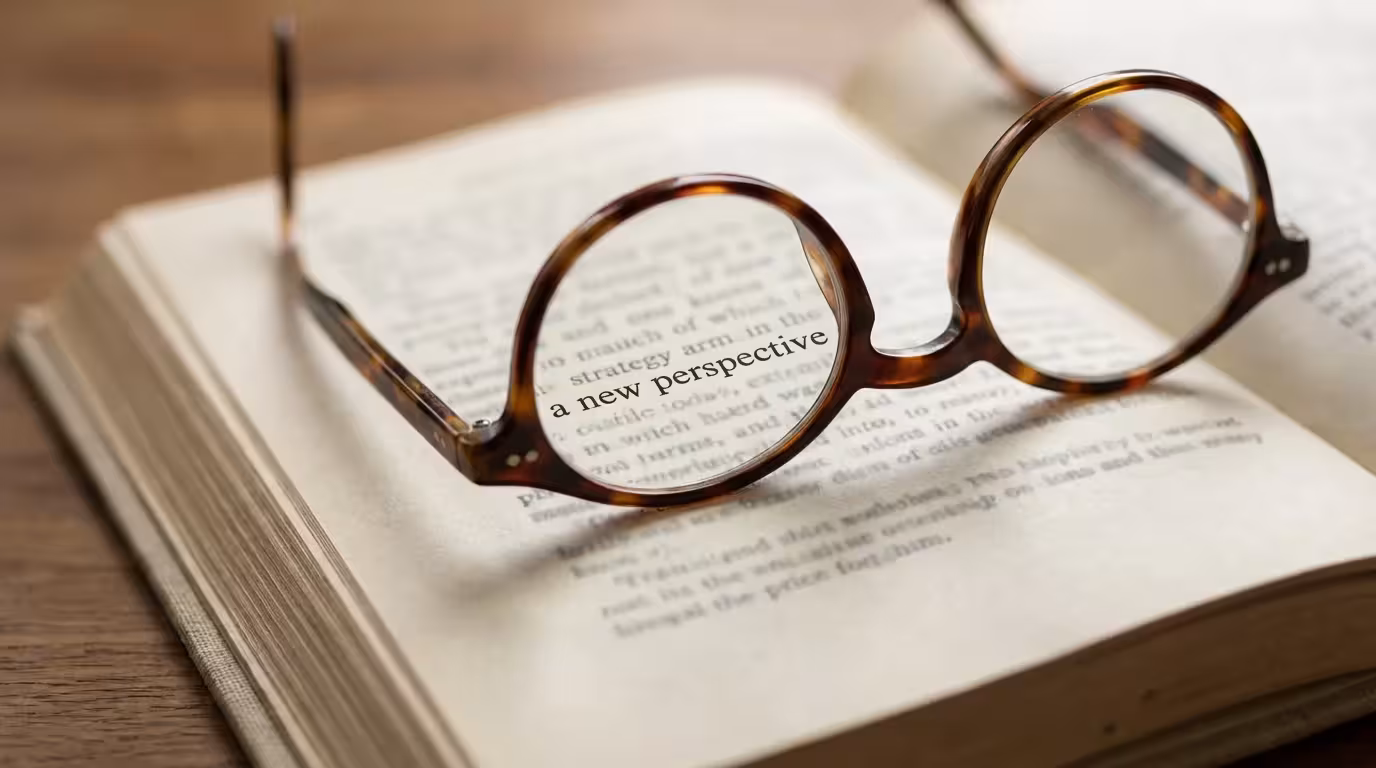 A macro photograph of reading glasses resting on an open book, magnifying the text.
