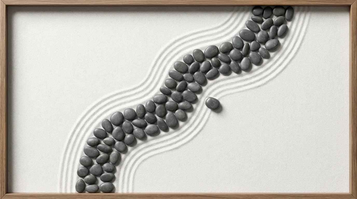 Flat lay of a meandering path of stones on raked white sand, symbolizing a journey.